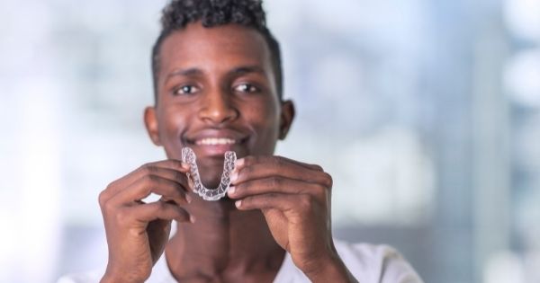 young man with invisalign tray and smile on his face