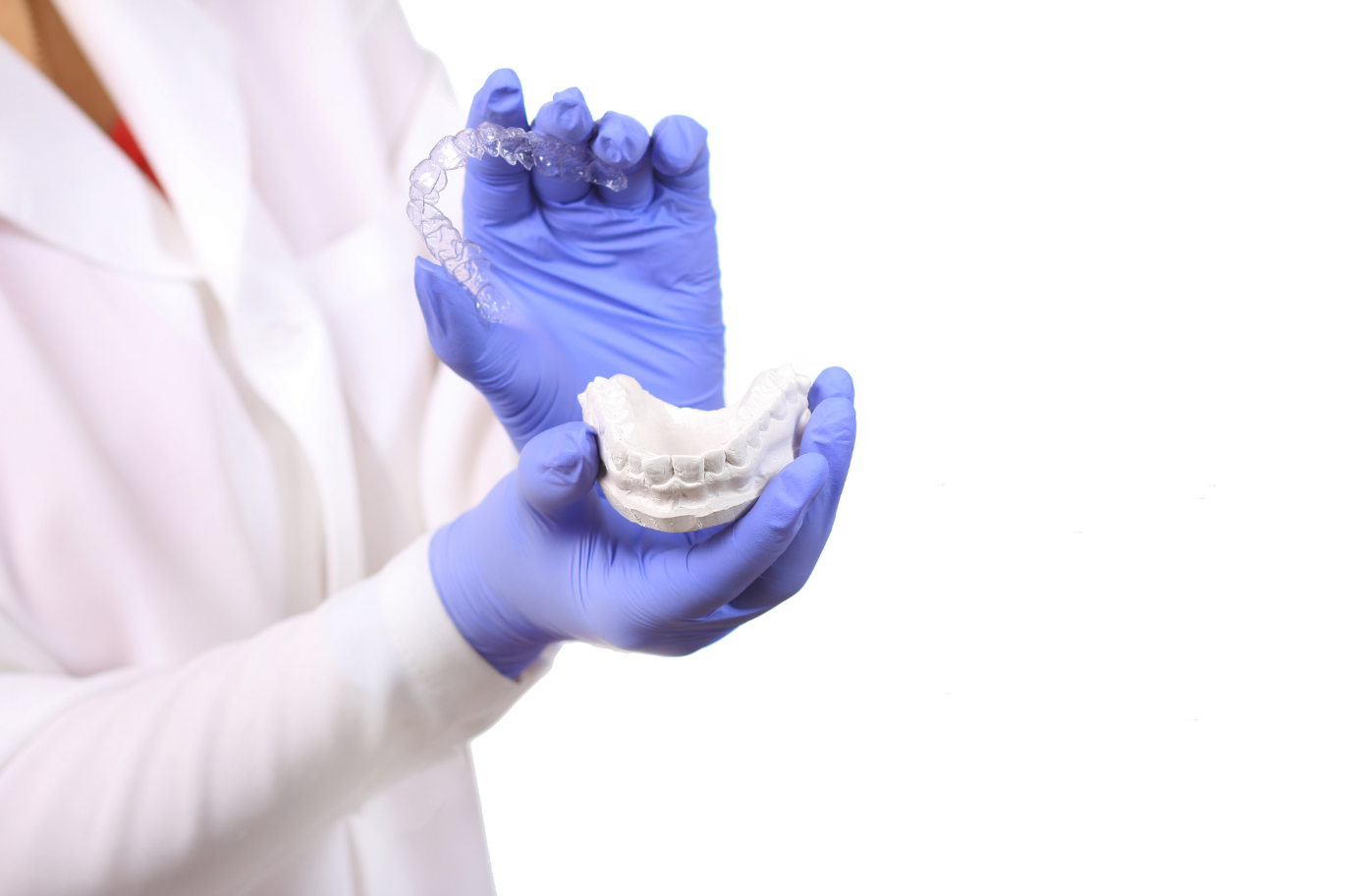 dentist with blue gloves holding clear night guard and mould